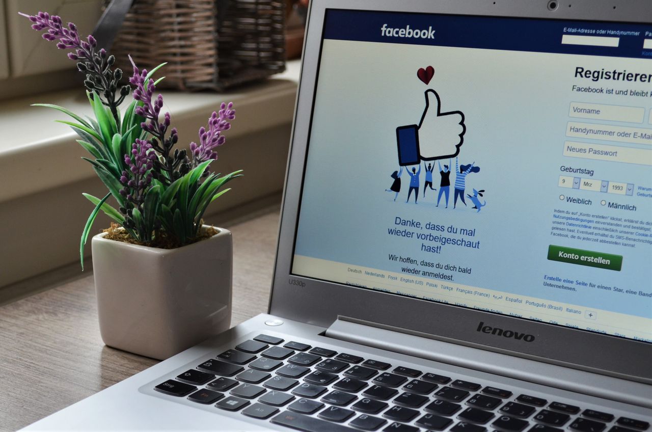 our-story A Lenovo laptop displaying Facebook login beside a lavender plant indoors.